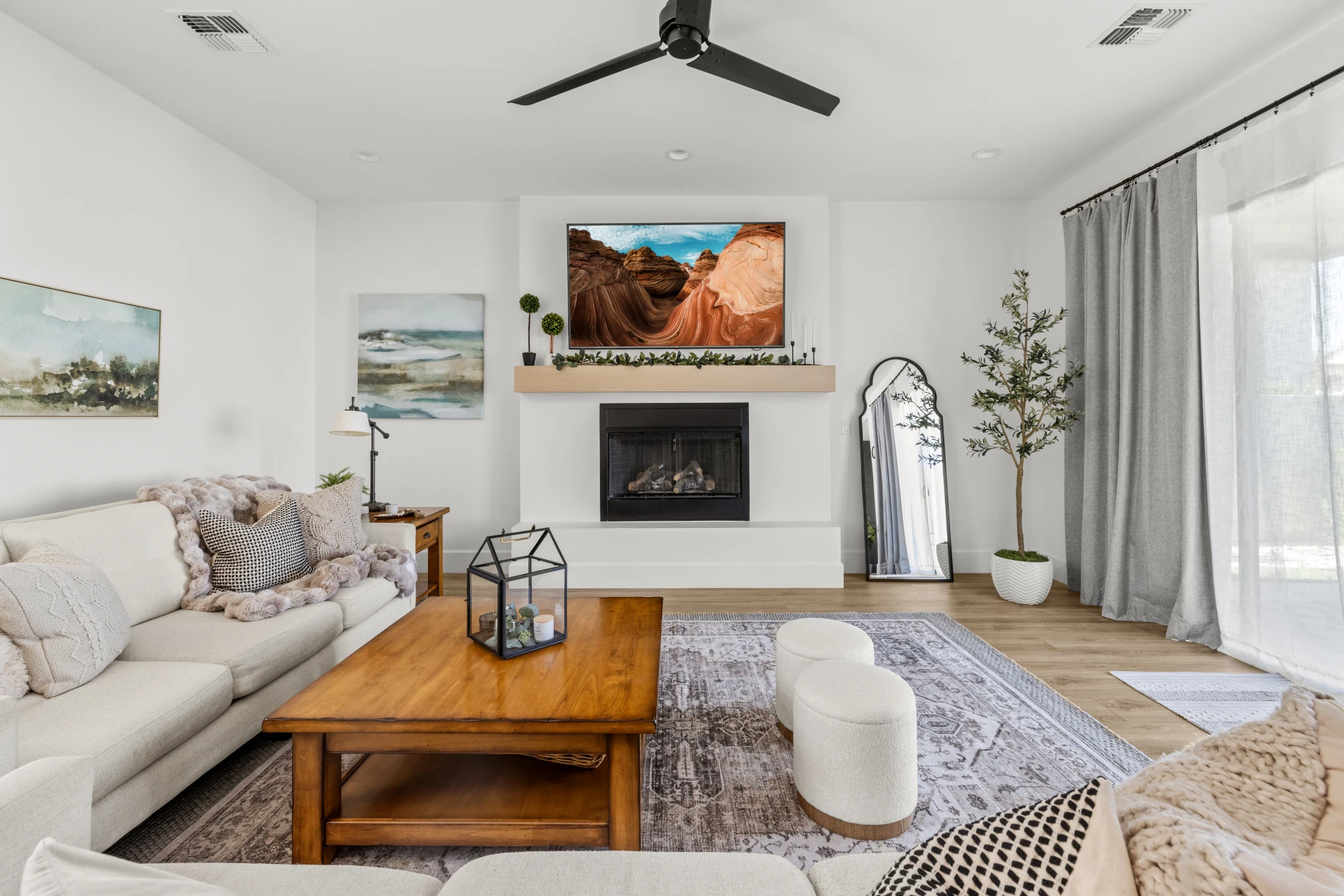 A modern and inviting living room with a fireplace, neutral decor, and natural light. Photographed by Shane Baker Studios.