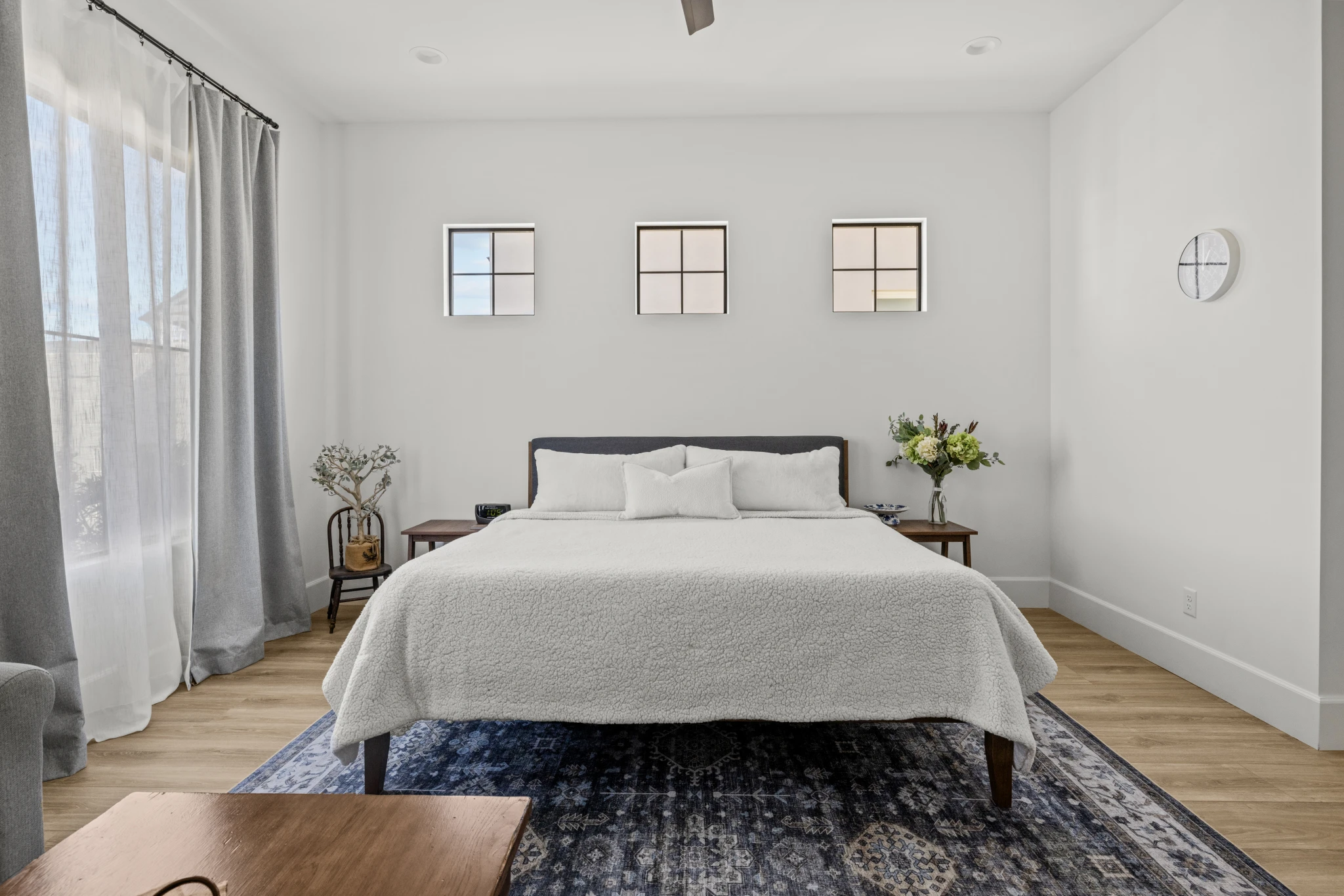 A modern and serene bedroom with a minimalist design, featuring a cozy bed, soft neutral tones, and natural light. Photographed by Shane Baker Studios.