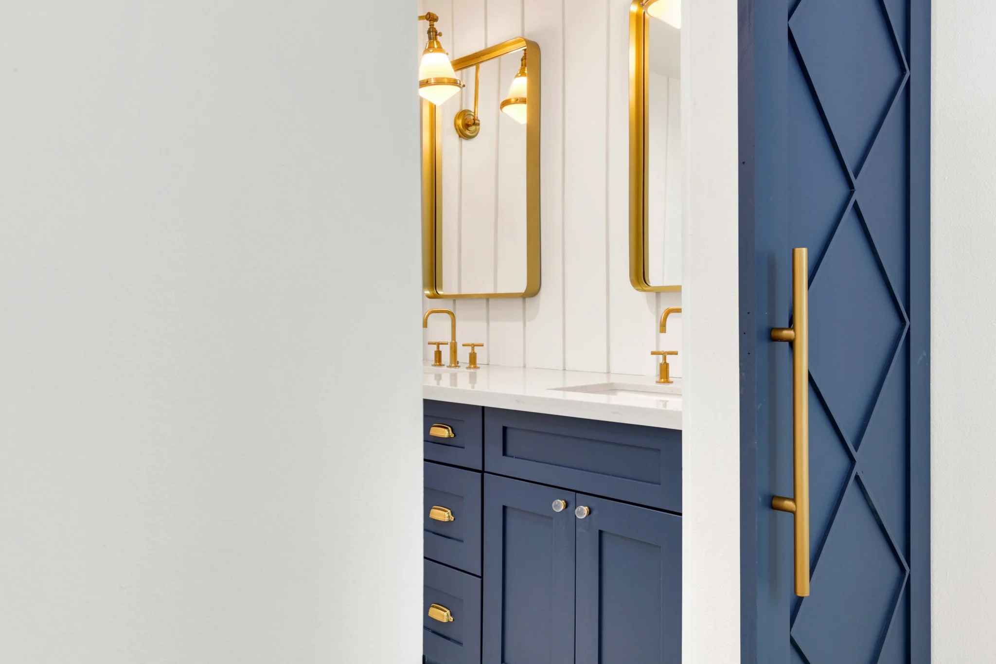 Modern bathroom with navy cabinetry, gold fixtures, and a sliding blue barn door.