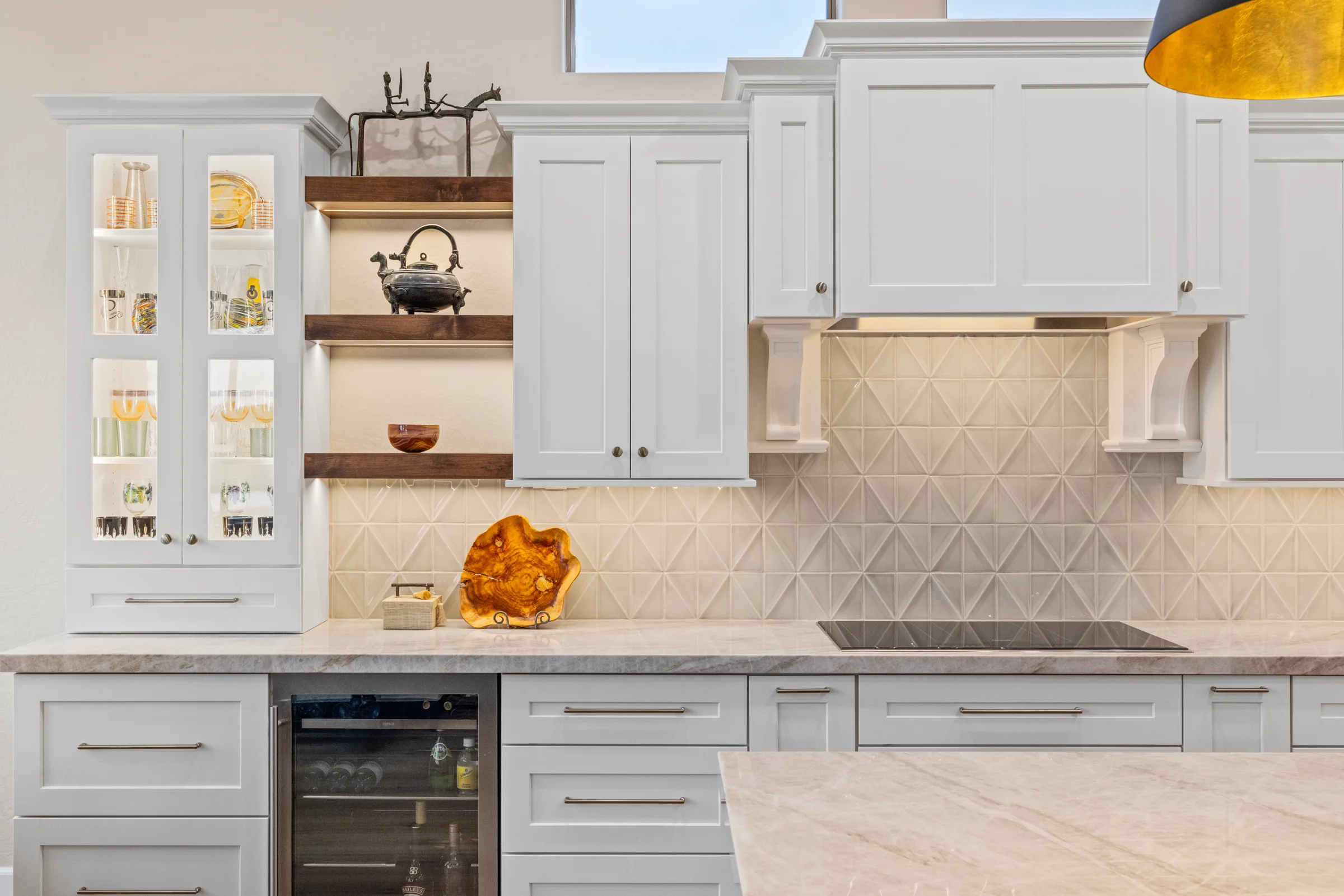 Close-up of a modern kitchen featuring white cabinetry, open wooden shelves, a geometric backsplash, and elegant countertop decor.